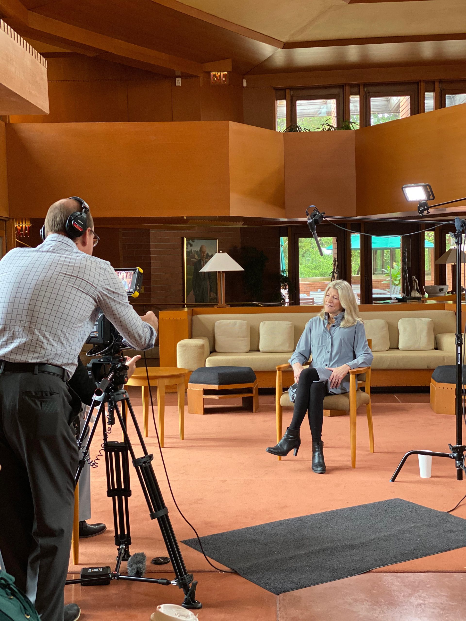 Woman sitting in chair, with man operating camera in foreground